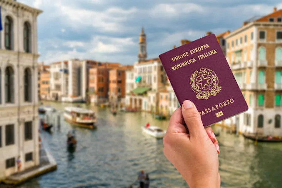 Venedik kanalı önünde tutulan İtalya pasaportu; İtalya dijital göçebe vizesi başvurusu için gerekli belgeler