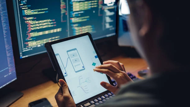 Mobil uygulama geliştirici tablette UI tasarımı ve arka planda kod ekranı